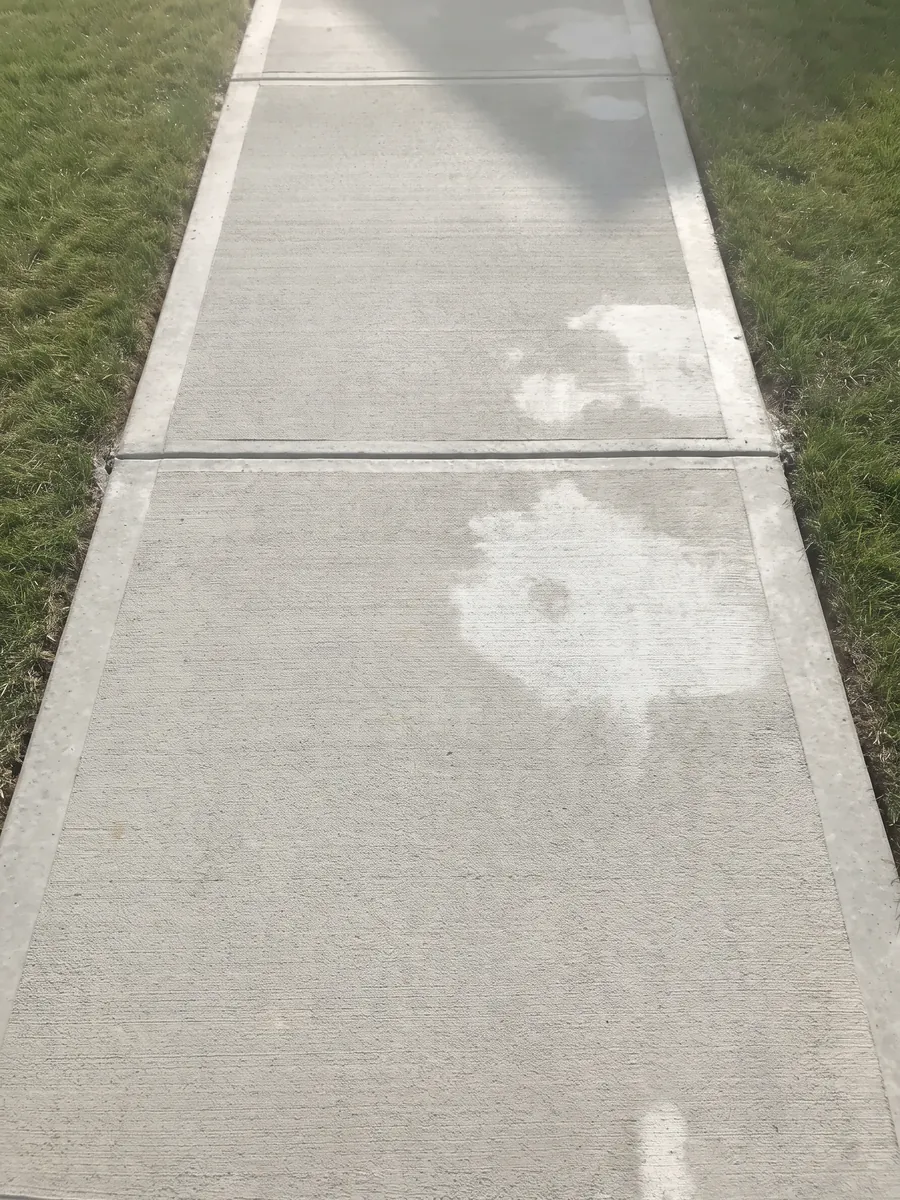 A broom-finished concrete walk with a tooled joint, still curing