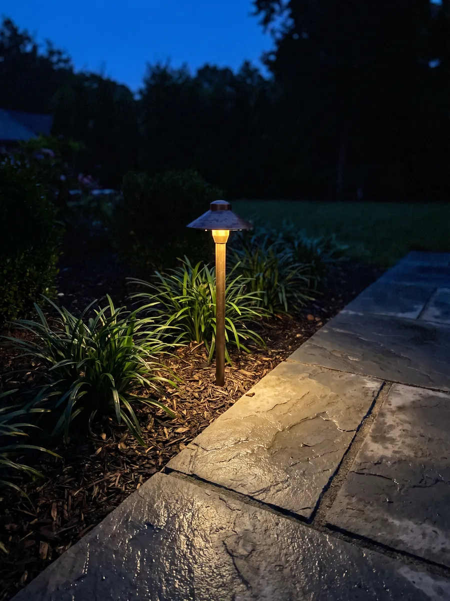A bronze path light on a bluestone walk at dusk