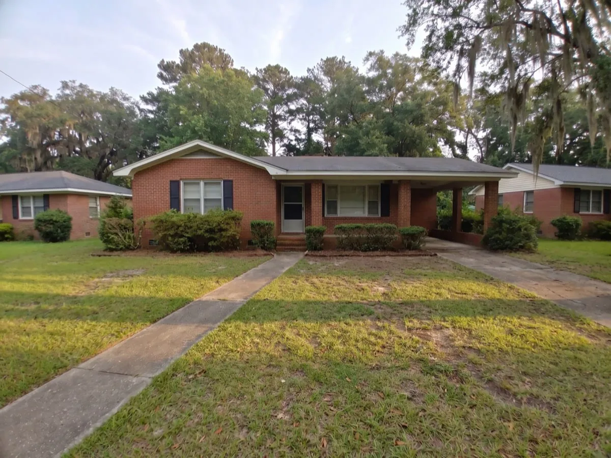 A cleared, mown yard in front of a brick ranch house