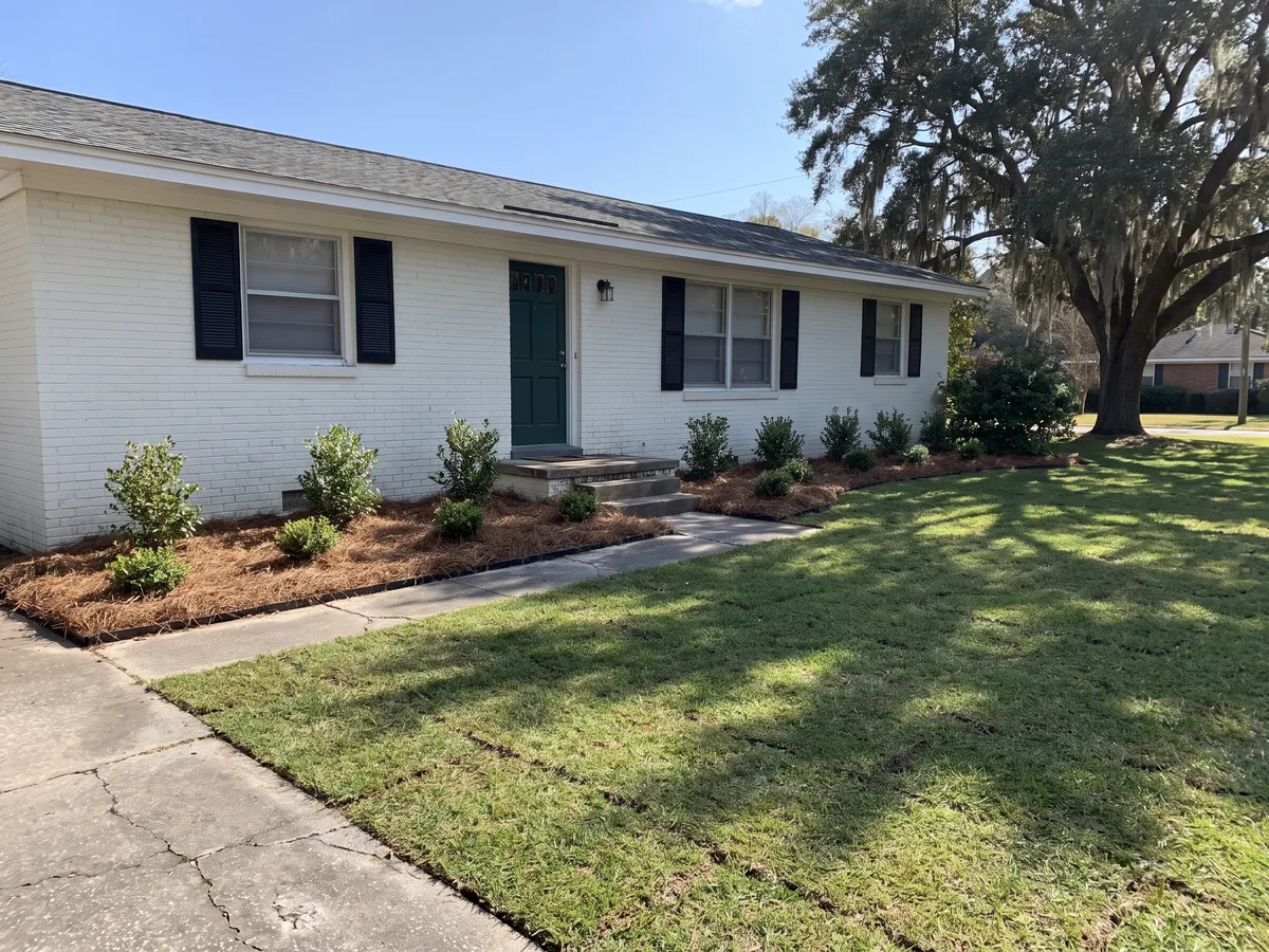 After: The same house with young shrubs planted in fresh pine straw beds and newly laid sod