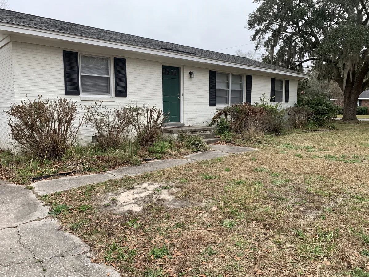 Before: A white painted brick ranch house with dead, leggy shrubs in bare beds and a thin, patchy lawn